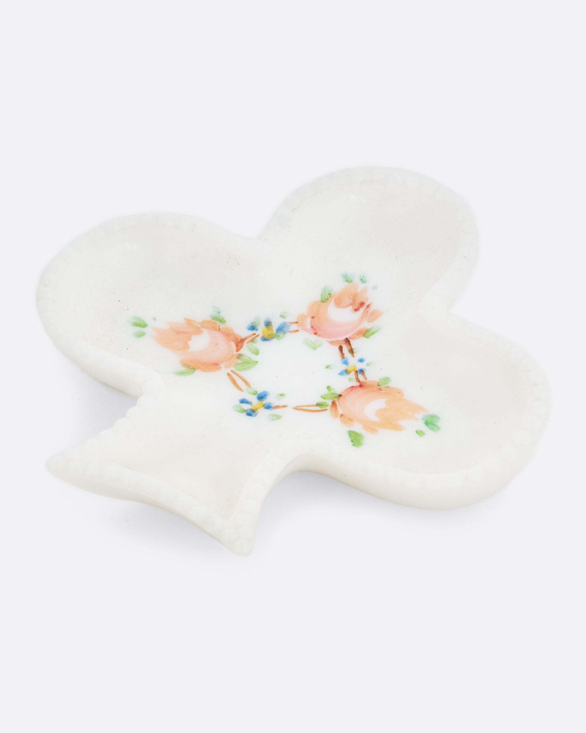 A club shaped white ceramic dish with a floral design. Shown at an angle from the top.