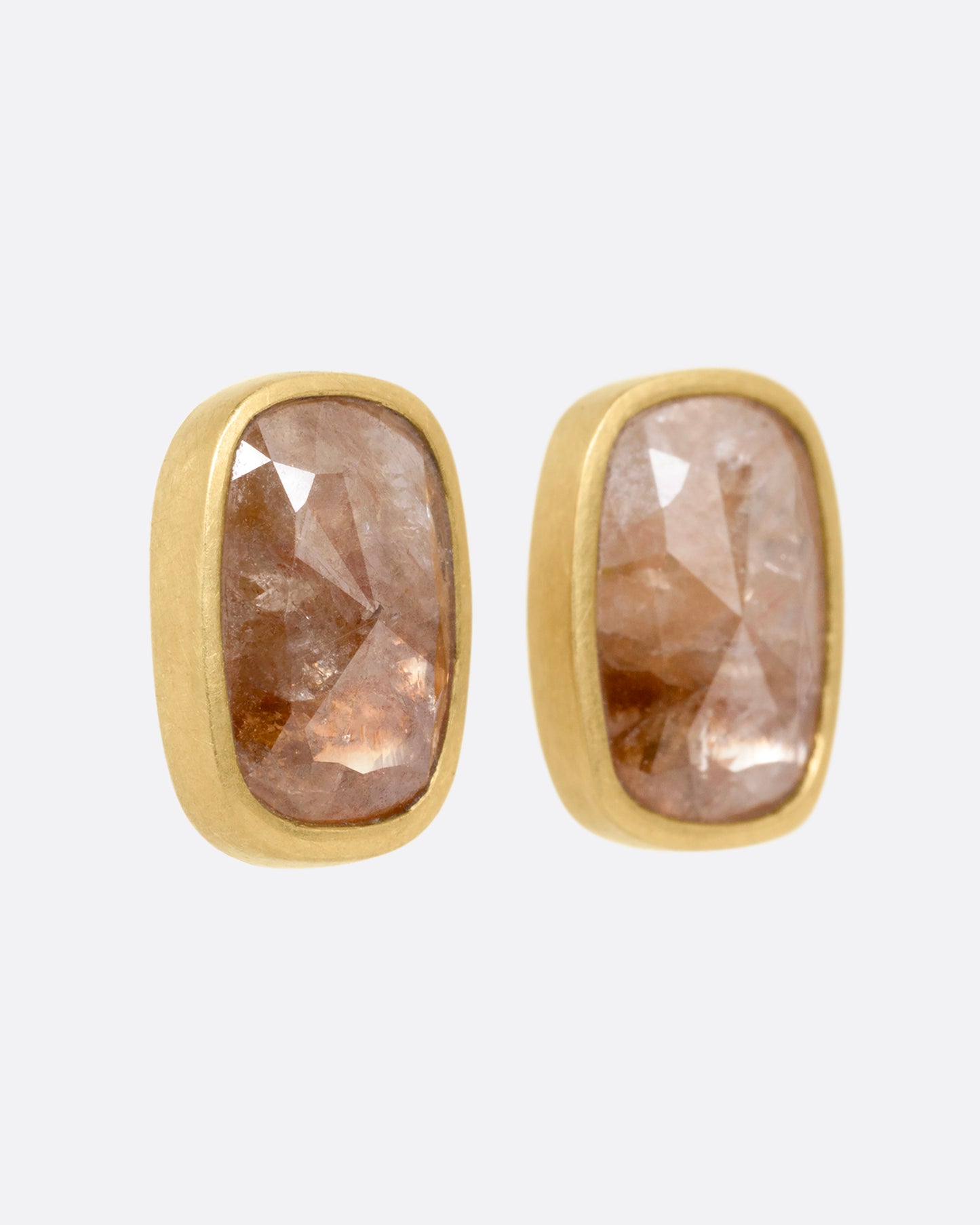 A pair of yellow gold rectangular salt and pepper stud earrings, shown from the side.