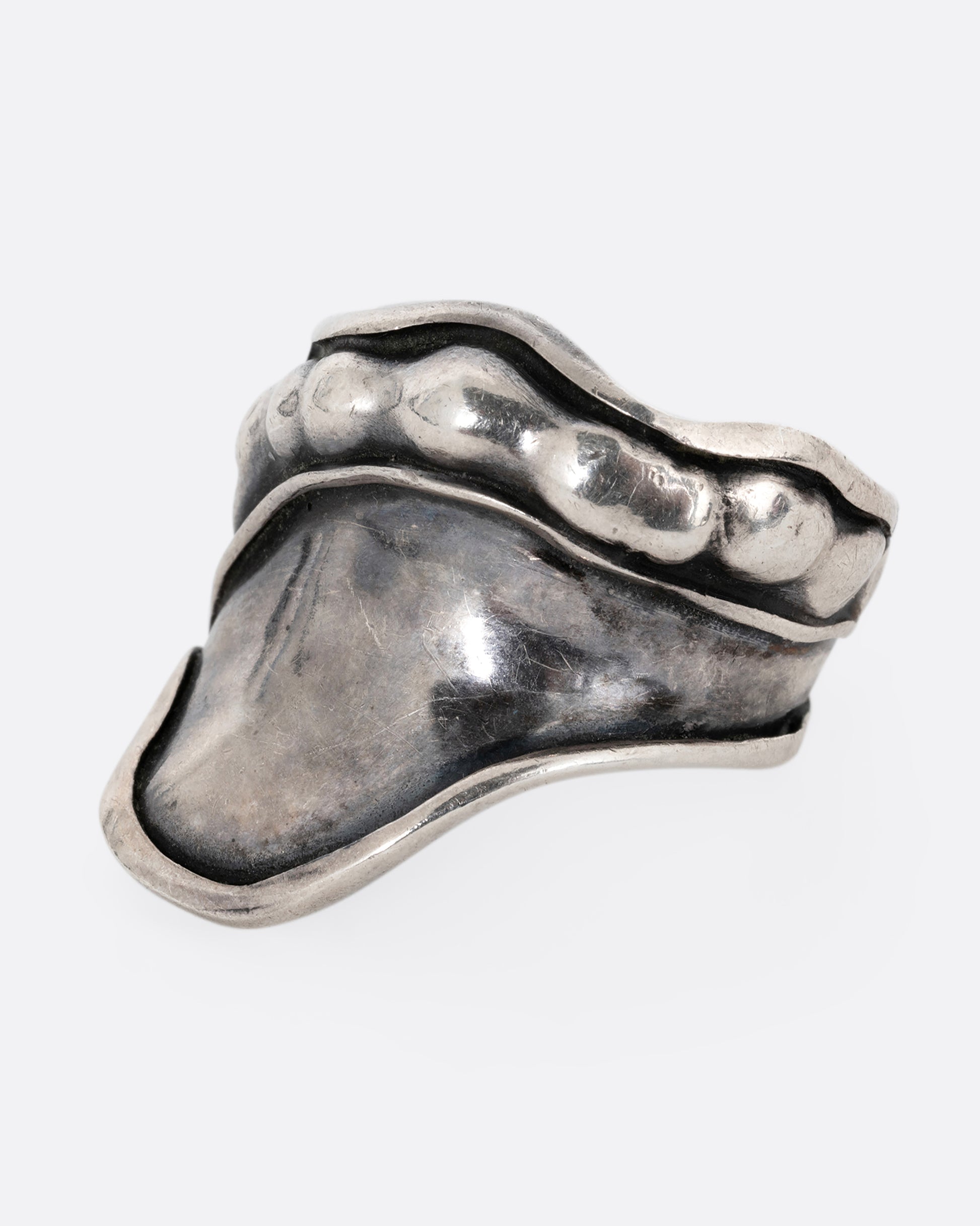 A silver leaf shaped wrap ring with silver drops along the top edge. Shown from the side.