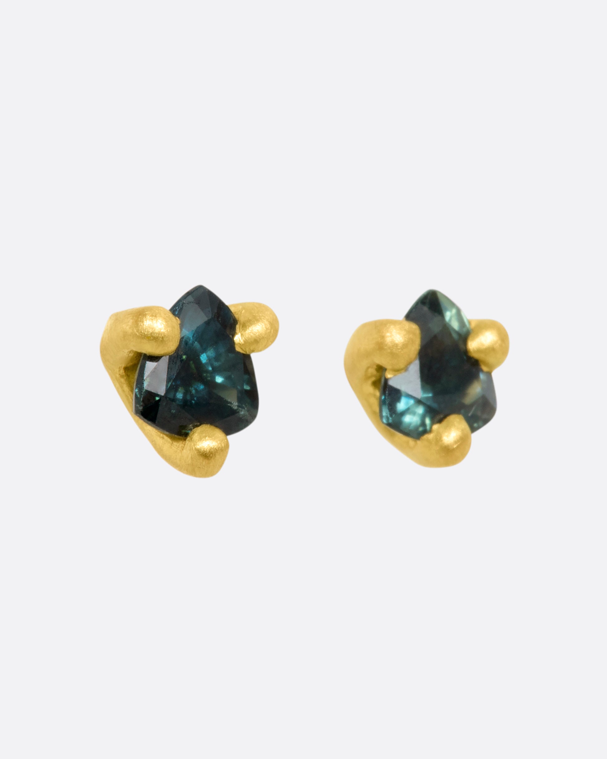 A pair of matte yellow gold prong set 4mm sapphire stud earrings. View from the side.