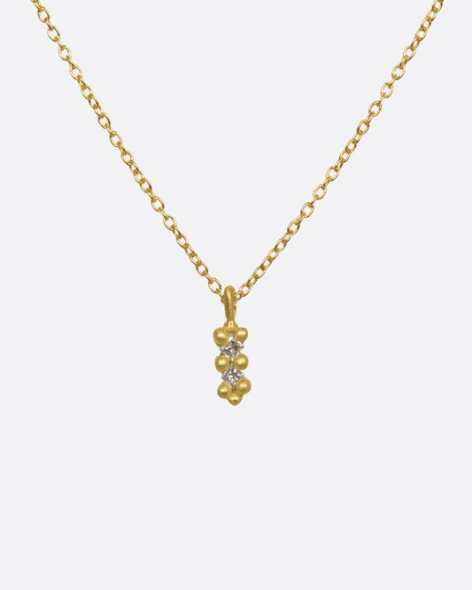 A yellow gold necklace with a double white diamond pendant. Shown from the front.