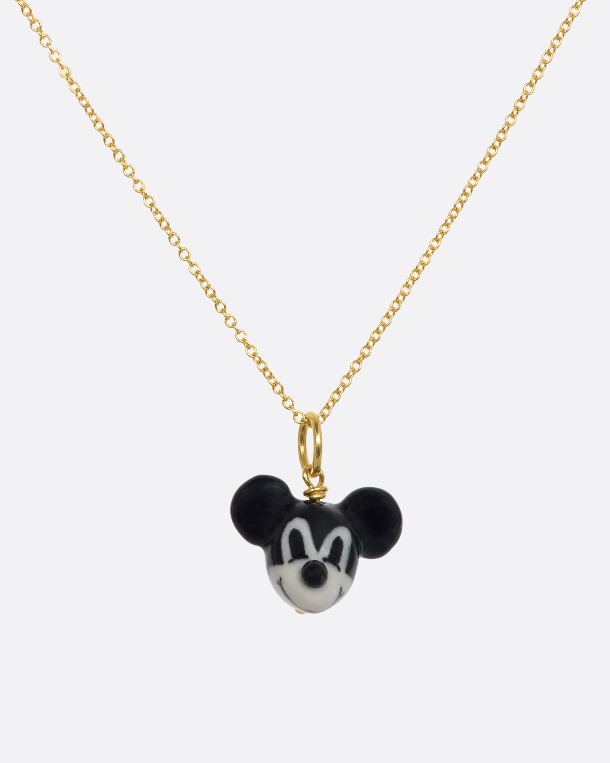 A three dimensional black and white era mickey mouse charm with a yellow gold bail. Hanging from a yellow gold chain.