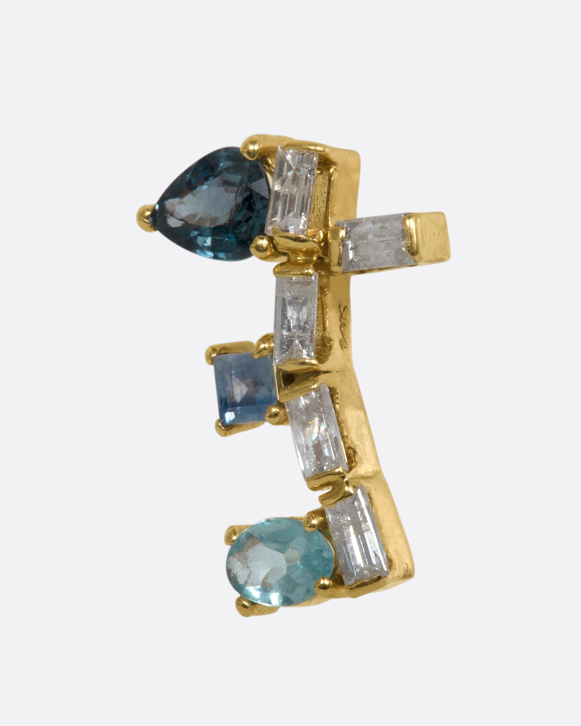 A yellow gold stud earring shaped like a botanical vine made of sapphire, apatite, and diamonds. Shown from the side.