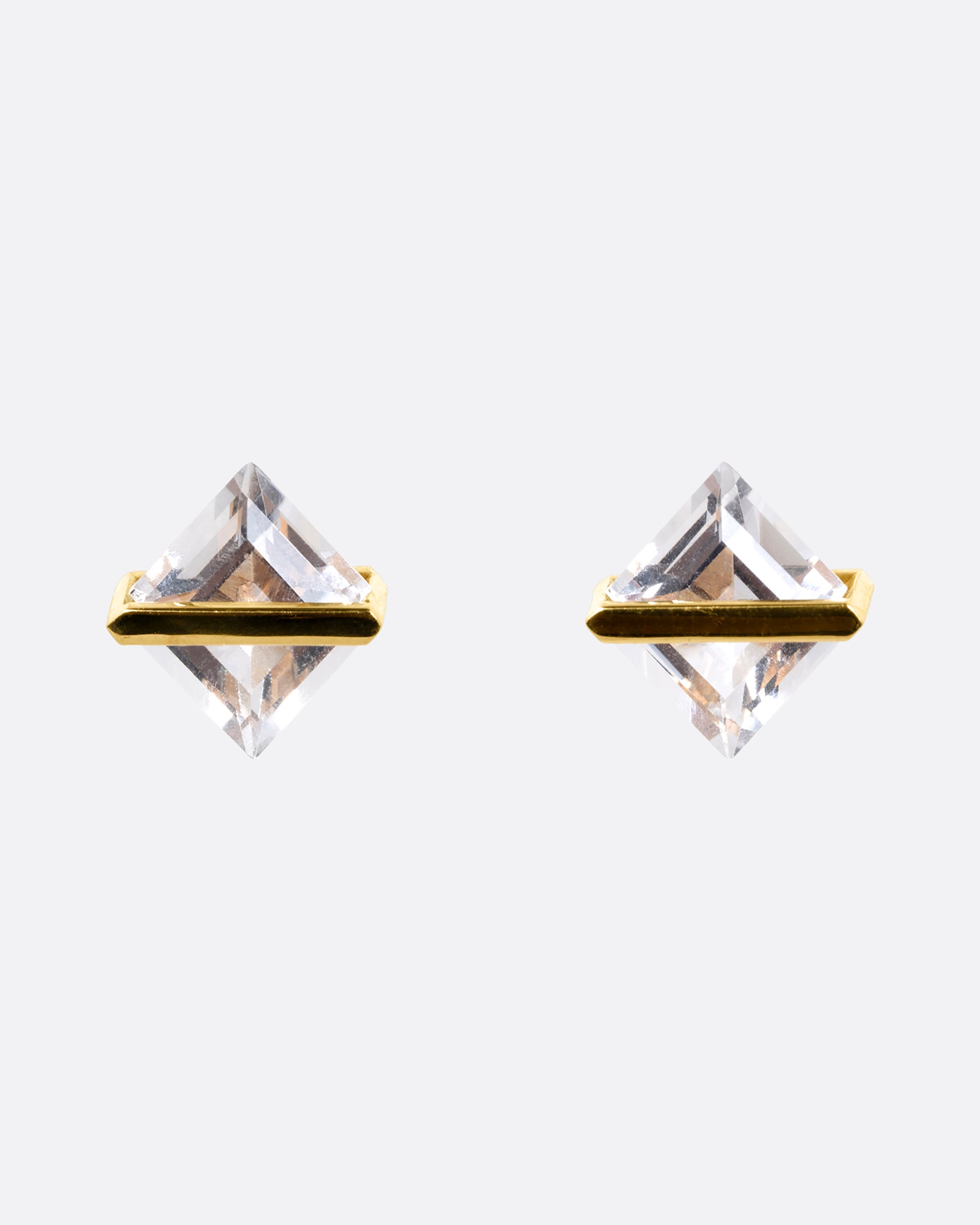 A pair of rhombus shaped quartzes, each in an open yellow gold bar stud earring setting. Shown from the front.