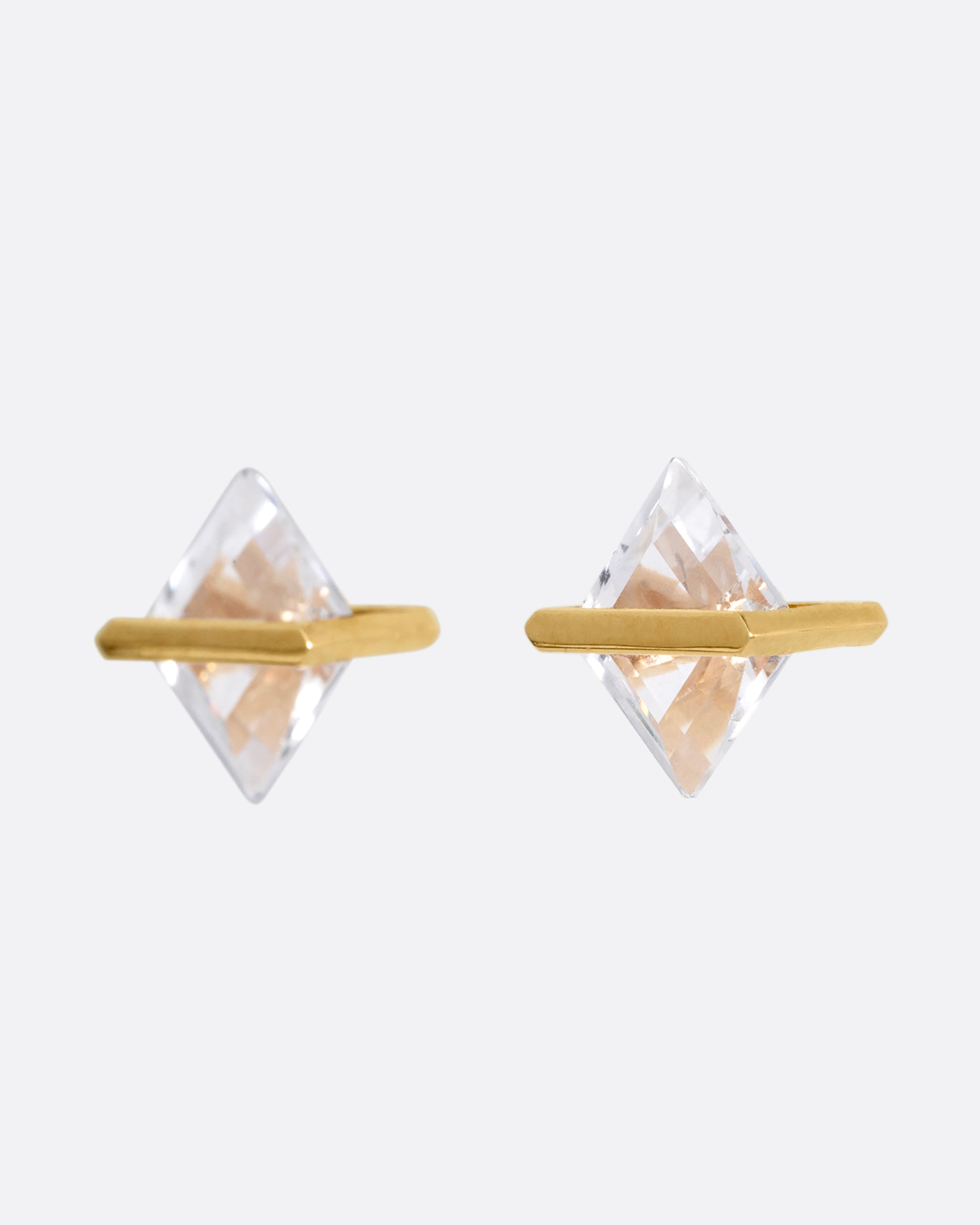 A pair of rhombus shaped quartzes, each in an open yellow gold bar stud earring setting. Shown from the side.