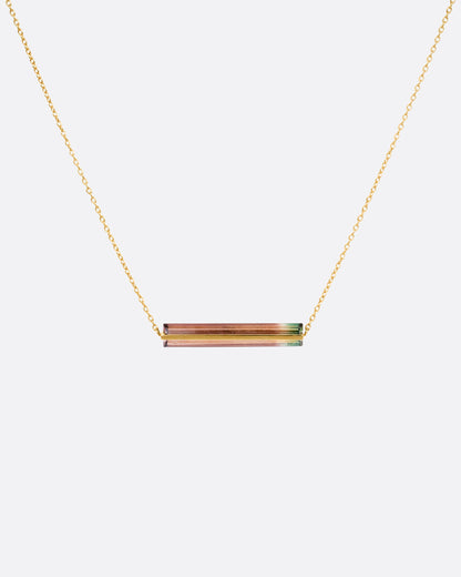 A yellow gold cable chain necklace with a watermelon tourmaline and gold bar, shown from the front.