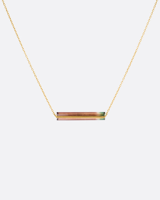 A yellow gold cable chain necklace with a watermelon tourmaline and gold bar, shown from the front.