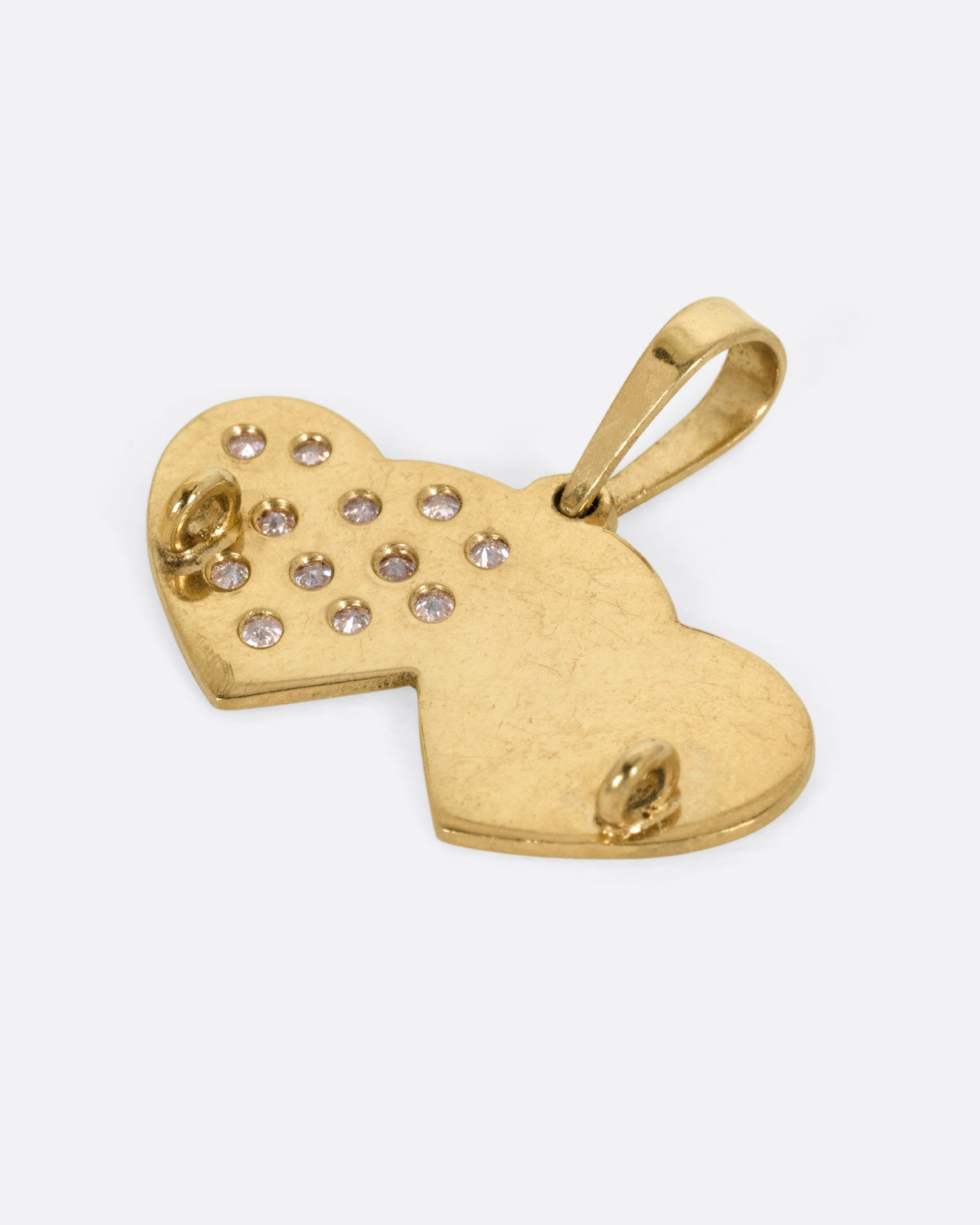 A yellow gold double heart charm with pavé diamonds over a stipple finish on one heart. Shown from the back.