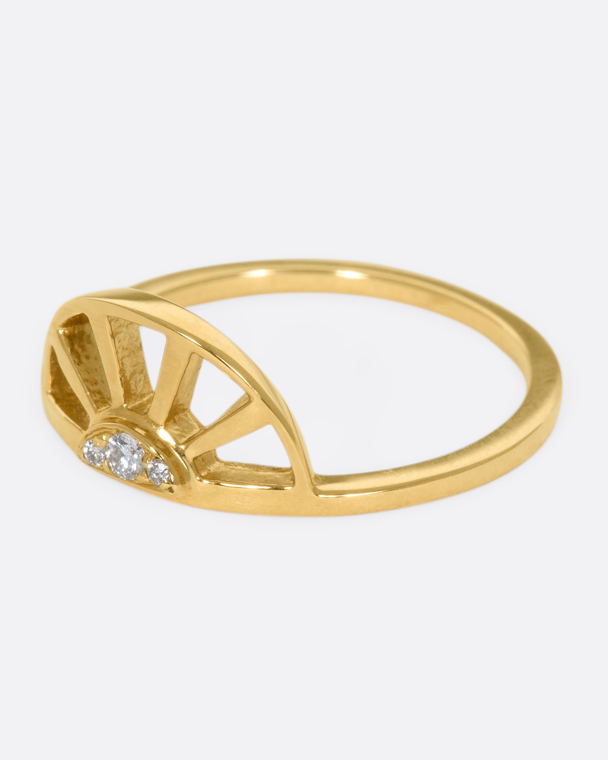 A yellow gold ring with a sun at the center and three white diamonds. Shown from the side.