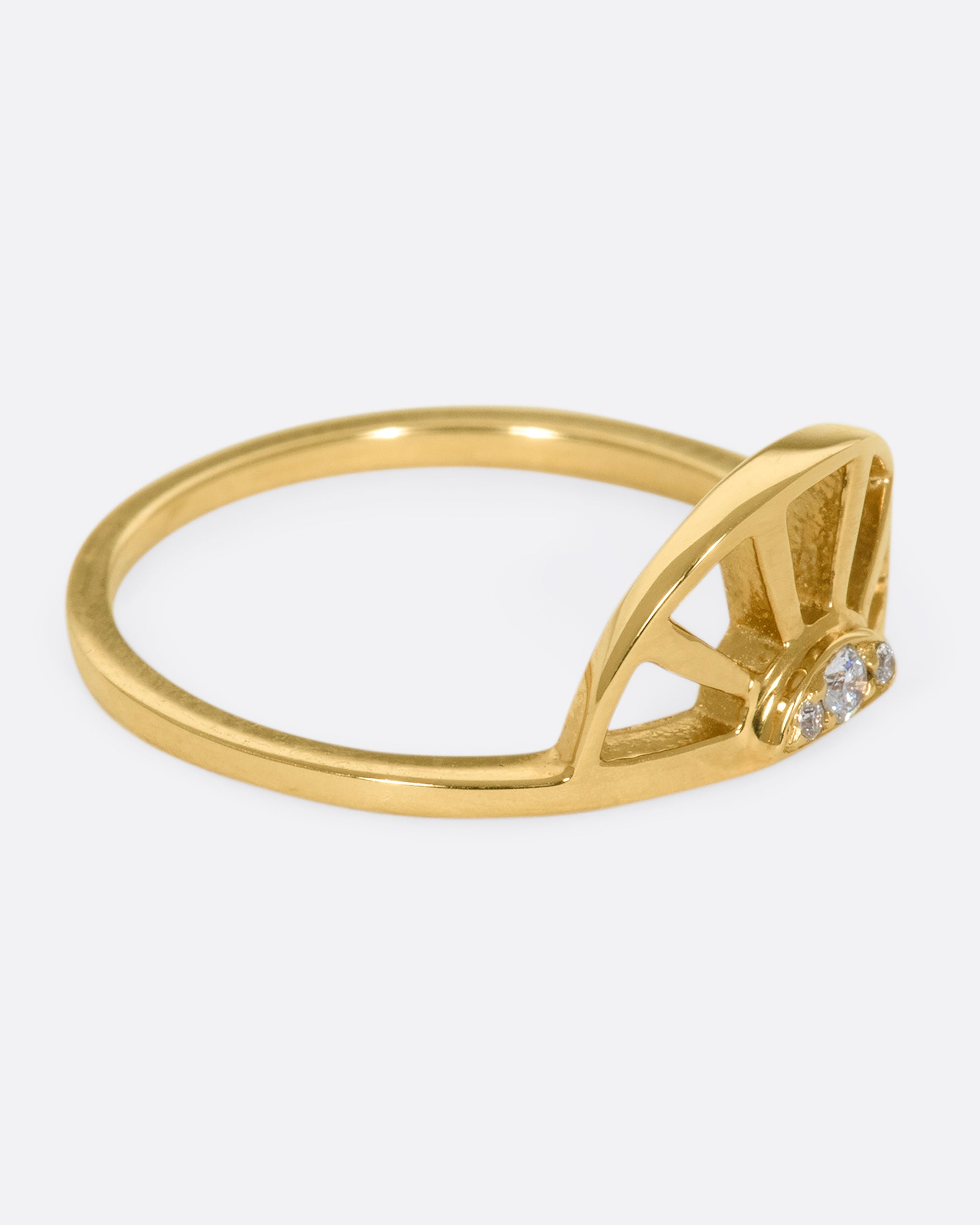 A yellow gold ring with a sun at the center and three white diamonds. Shown from the side.