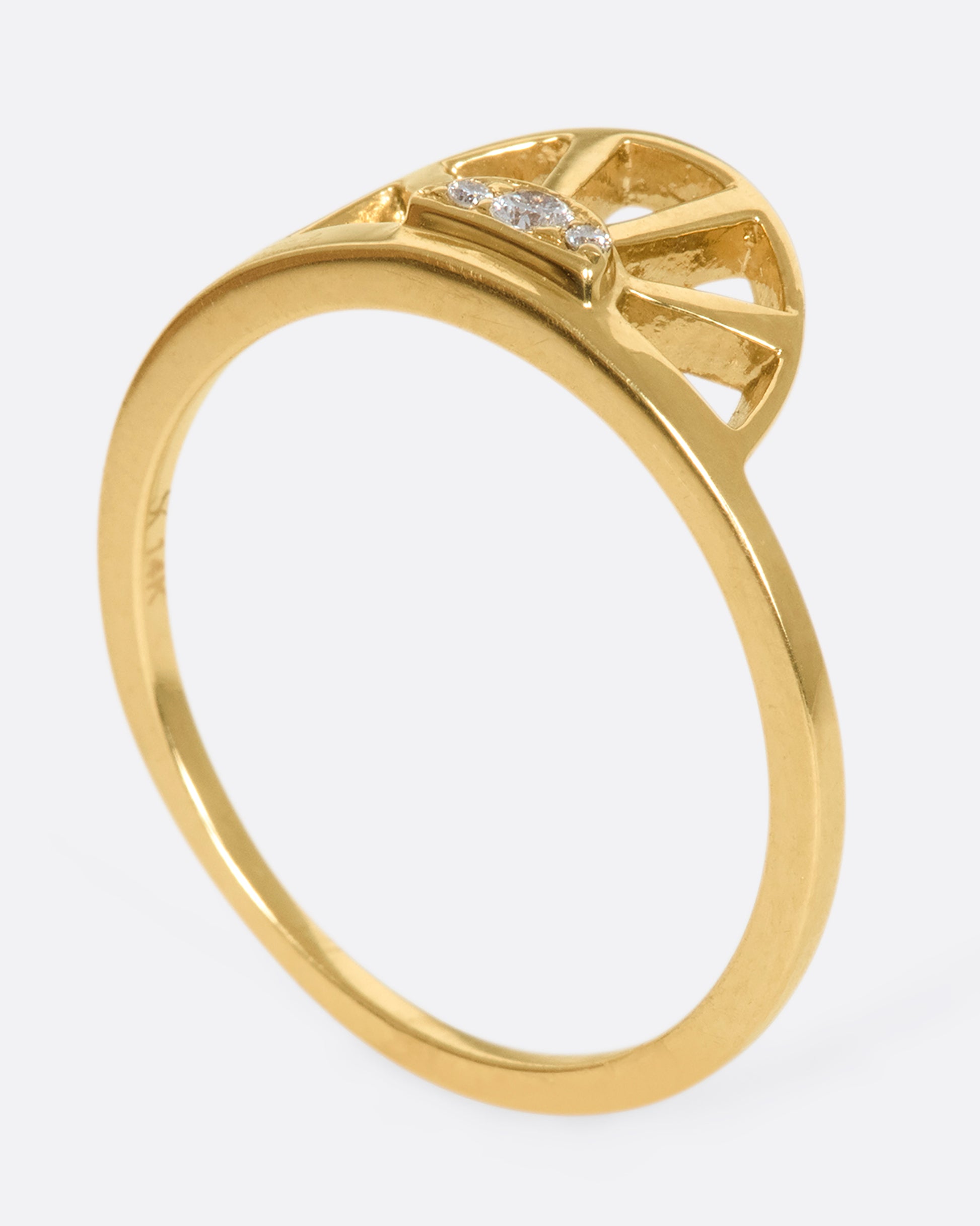 A yellow gold ring with a sun at the center and three white diamonds. Shown standing up from the side.