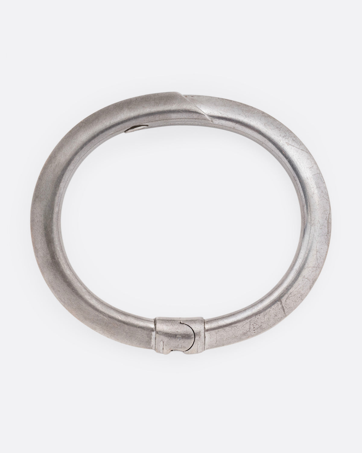 A silver wrap bracelet with hinged back, shown from the top.