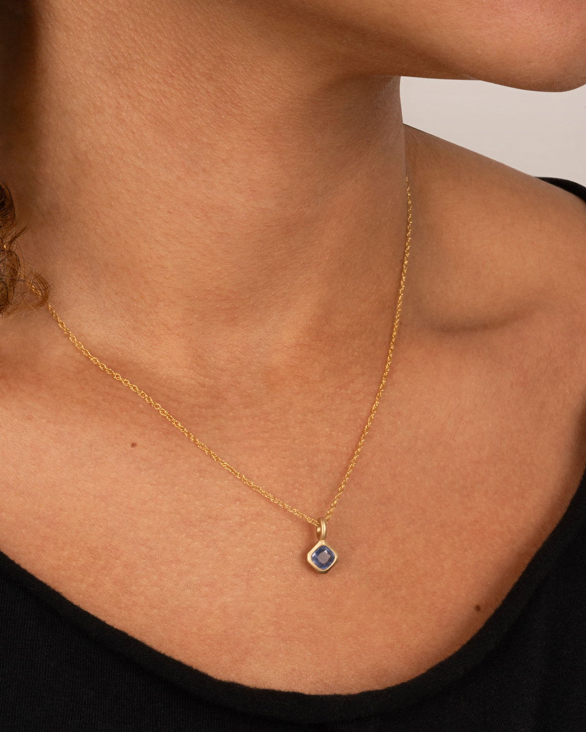 Yellow gold blue sapphire pendant necklace worn at the collarbone