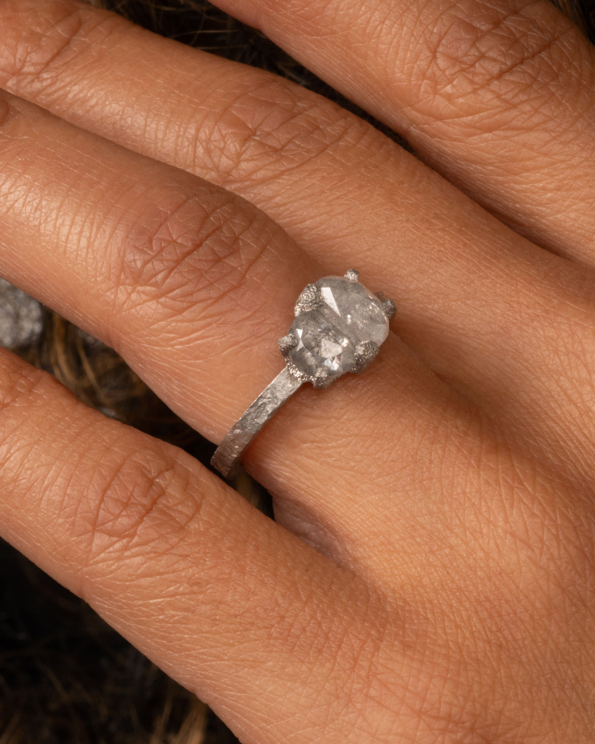 A platinum ring with two prong set rose cut diamonds, shown on a person.