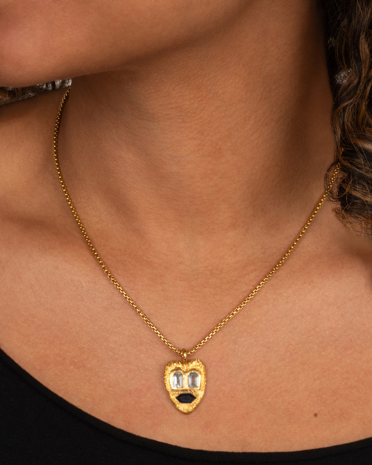 Oraik one-of-a-kind Heart Face pendant in 22k yellow gold worn on a chain, two aquamarine eyes and a blue sapphire mouth on a textured gold heart