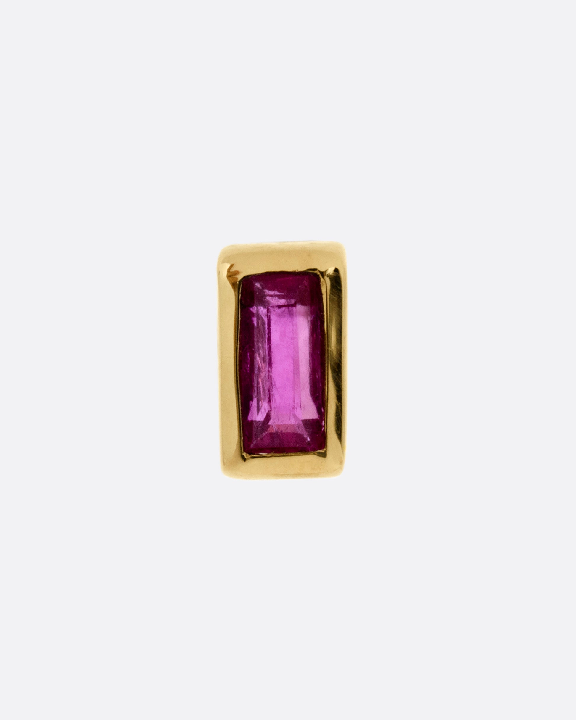 A yellow gold stud earring with a baguette cut ruby, shown from the front.