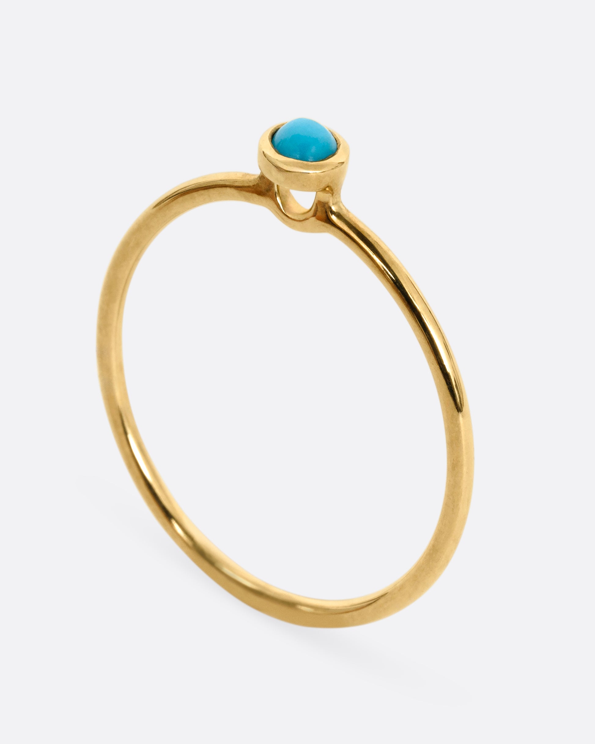A yellow gold ring with a round turquoise. Shown from the side standing up.