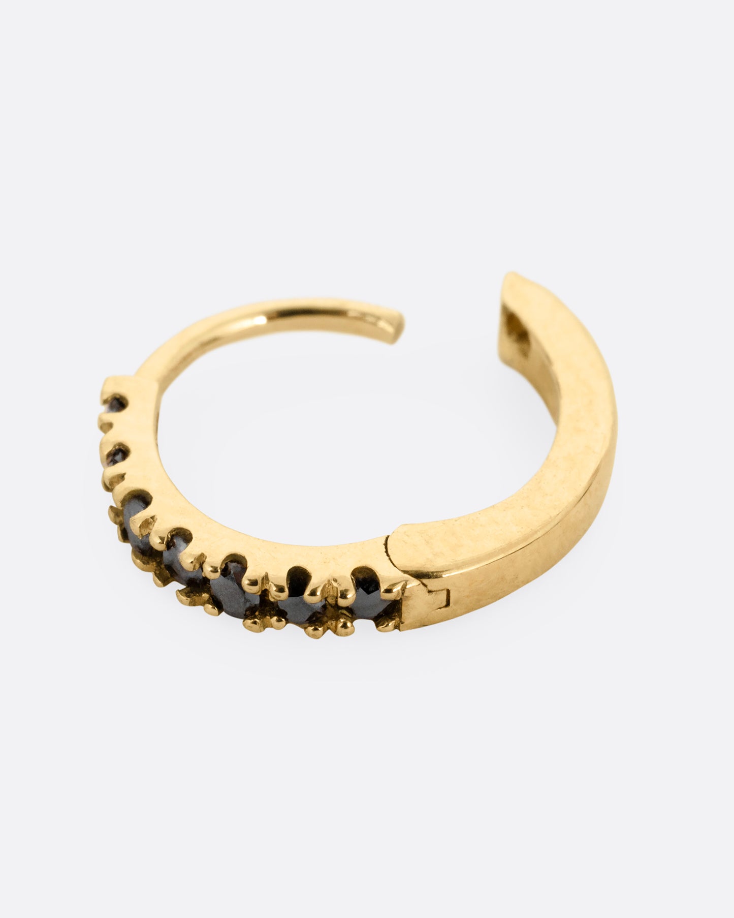 A yellow gold hinged hoop earring with black pavé diamonds, shown open from the side.