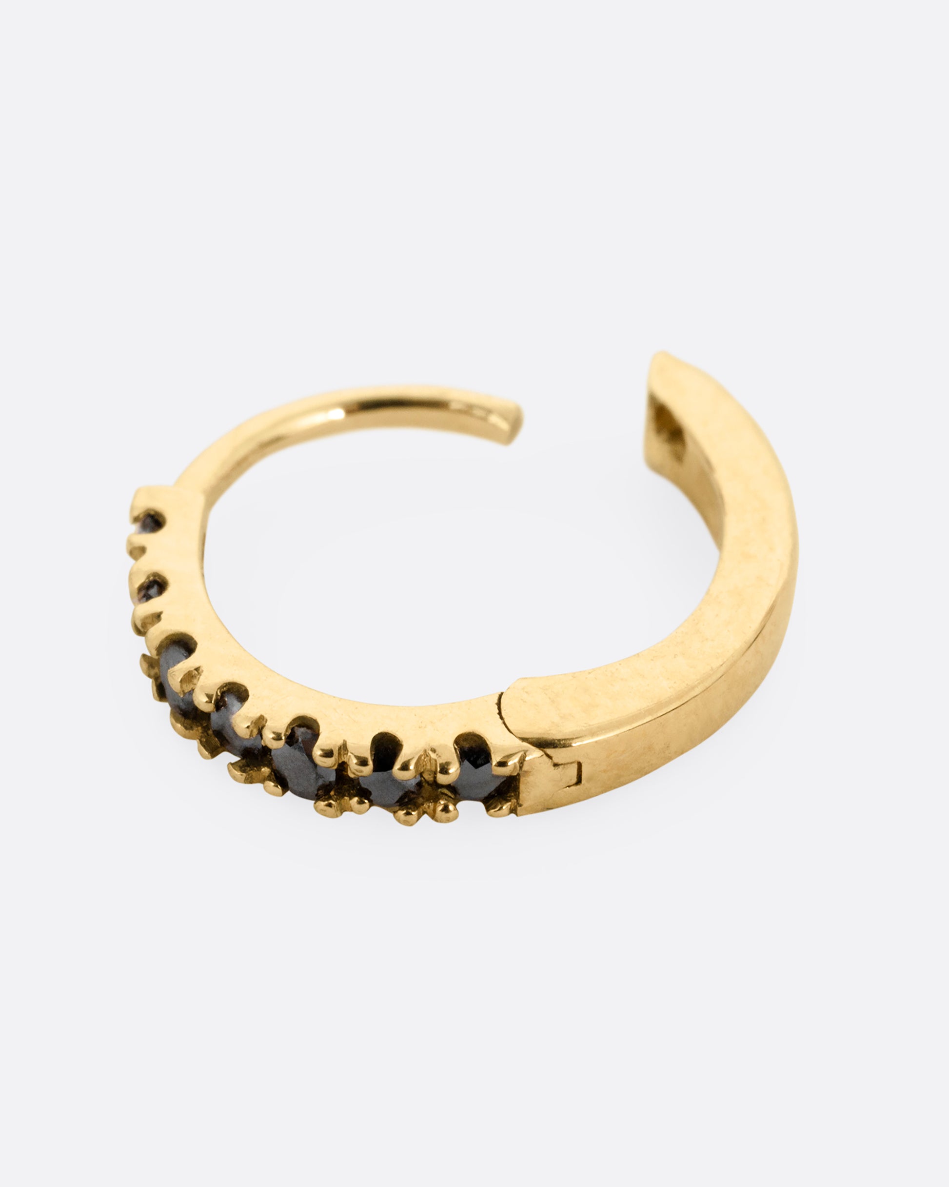 A yellow gold hinged hoop earring with black pavé diamonds, shown open from the side.