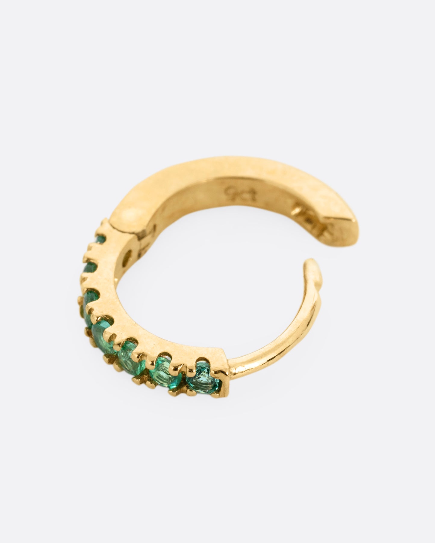 A yellow gold hinged hoop earring with pavé emeralds, shown open from the side.