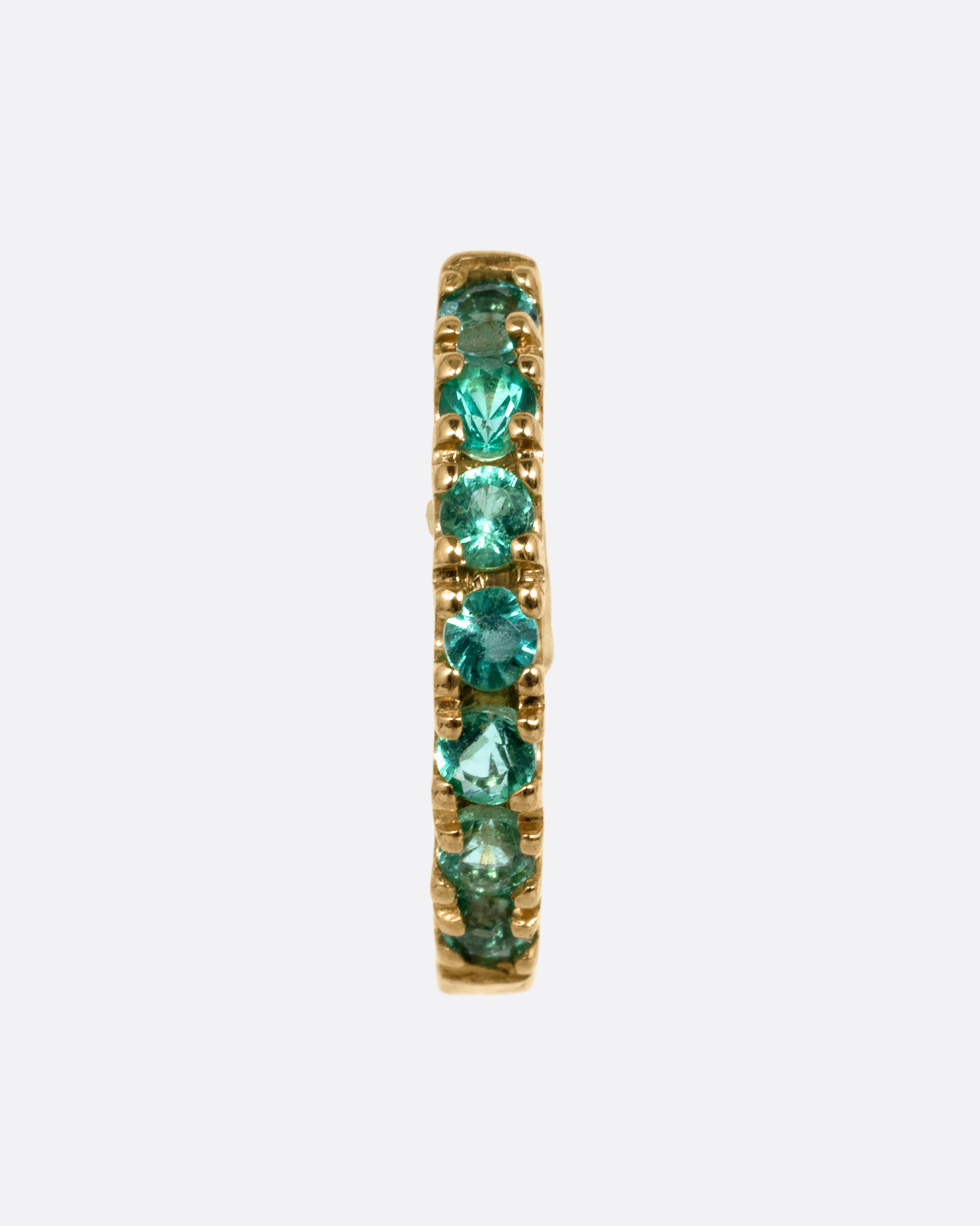 A yellow gold hinged hoop earring with pavé emeralds, shown from the front.