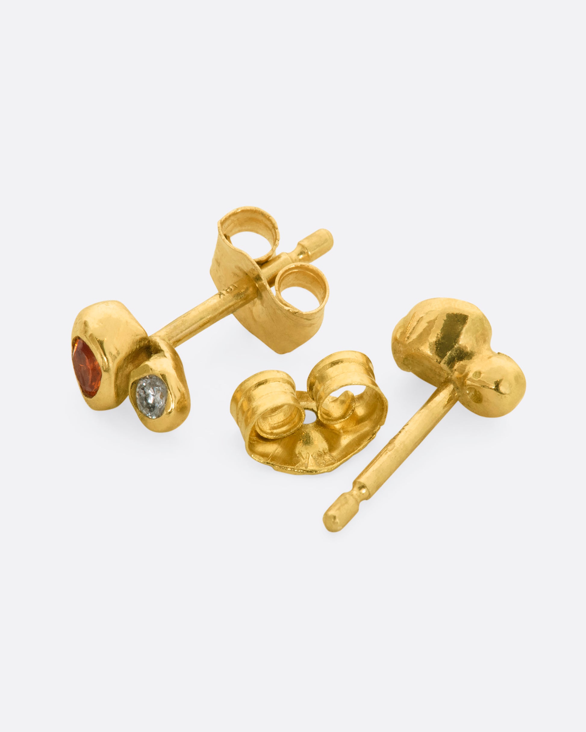 A pair of yellow gold bubble studs with orange sapphires and diamonds. Shown laying flat.