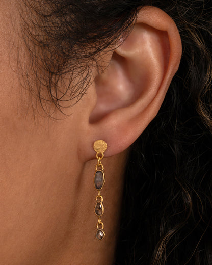 A yellow gold dangle earring with diamonds and sapphires, shown worn on an ear