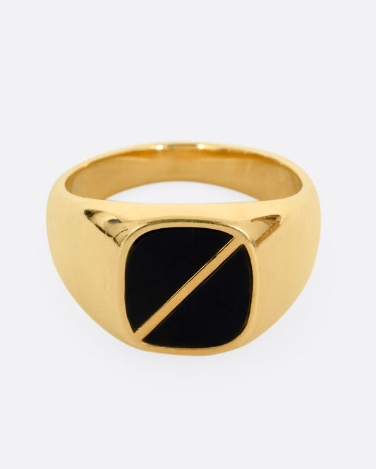 A yellow gold signet ring with a square onyx inlaid face and a diagonal split through its center. Shown from the front.