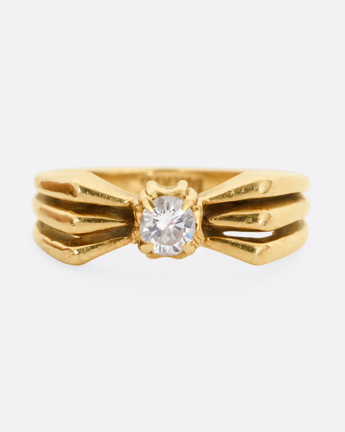 A yellow gold ring with a stacked silhouette and angular shoulders and a prong set diamond at the center. Shown from the front. 