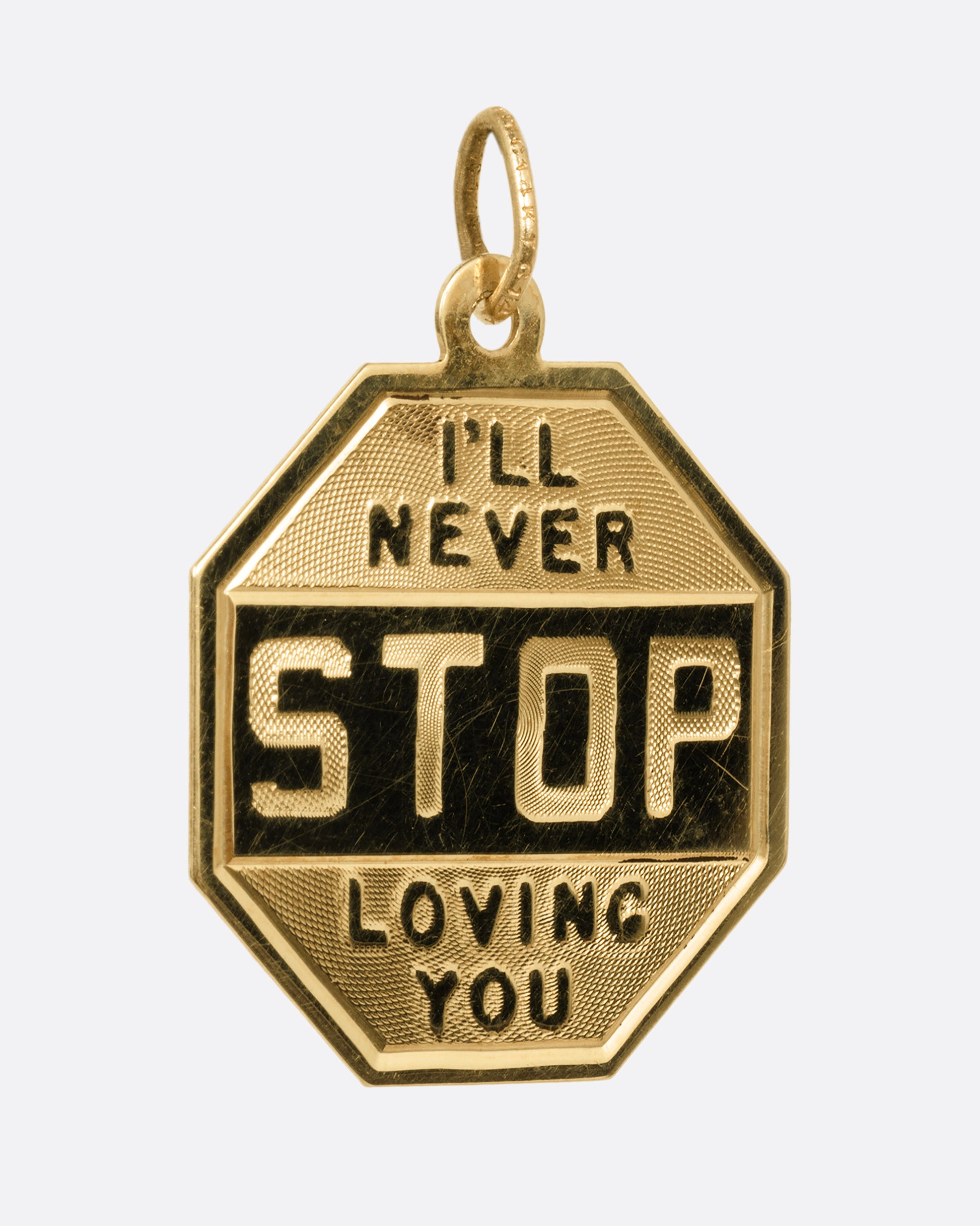A yellow gold stop sign pendant with 'I'll Never STOP Loving You' on its front and 'Happy Birthday 1964' engraved on its back. Shown from the front.