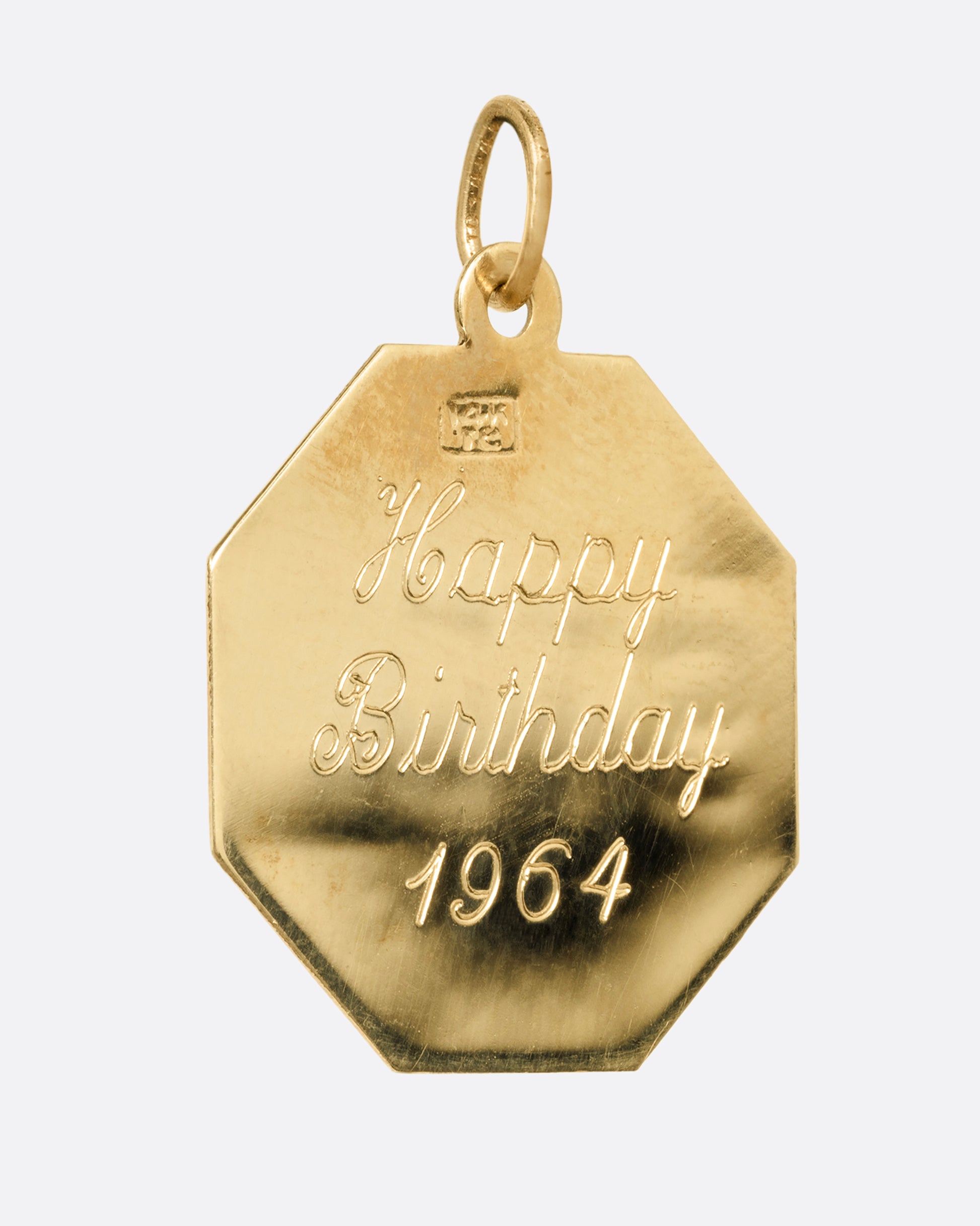 A yellow gold octagon shaped pendant with an engraved 'Happy Birthday 1964' on the back. Shown from the back.