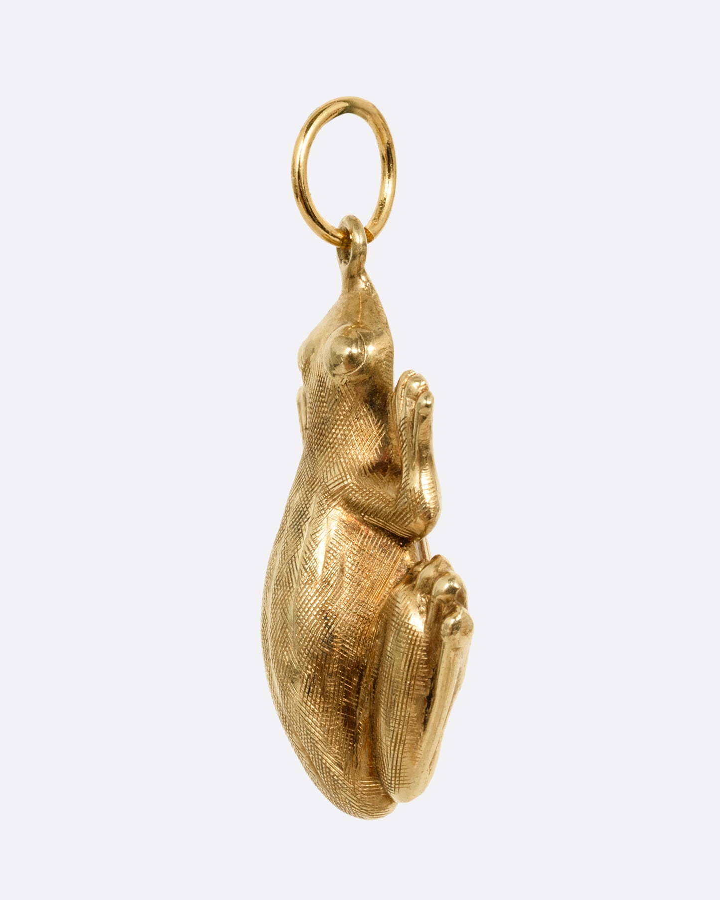 A yellow gold frog pendant shown from the side.