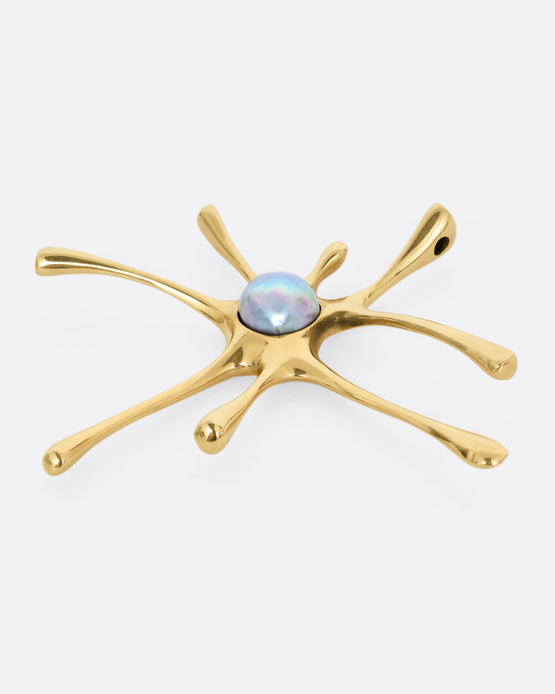 A yellow gold amoeba shaped pendant with a central pearl, shown lying flat from the side.