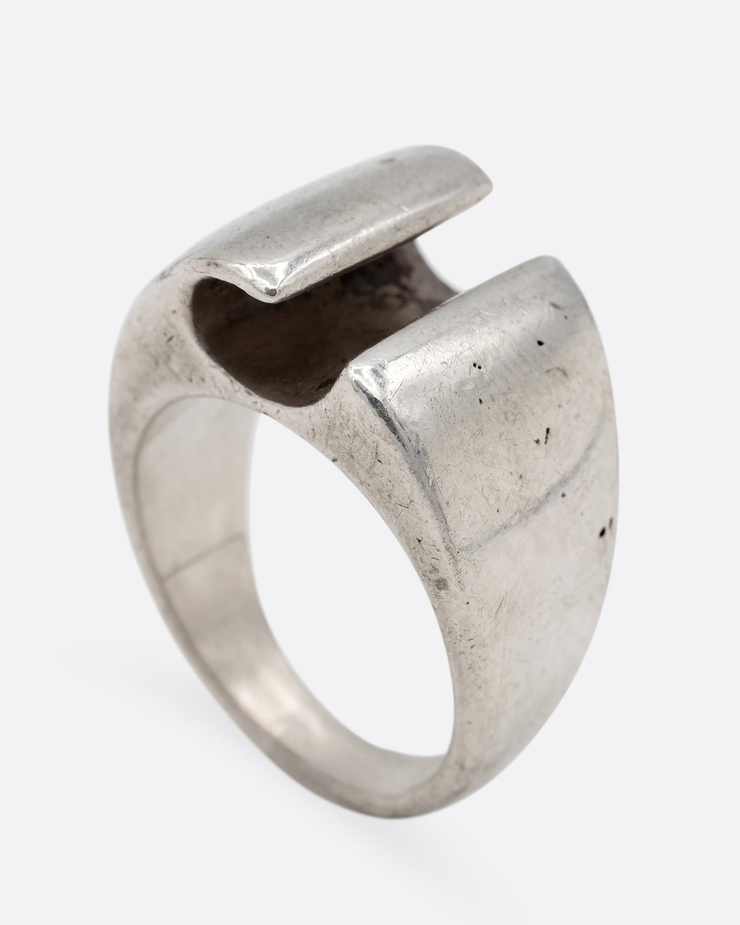 A silver ring with a notch in the front, shown from the side standing up.