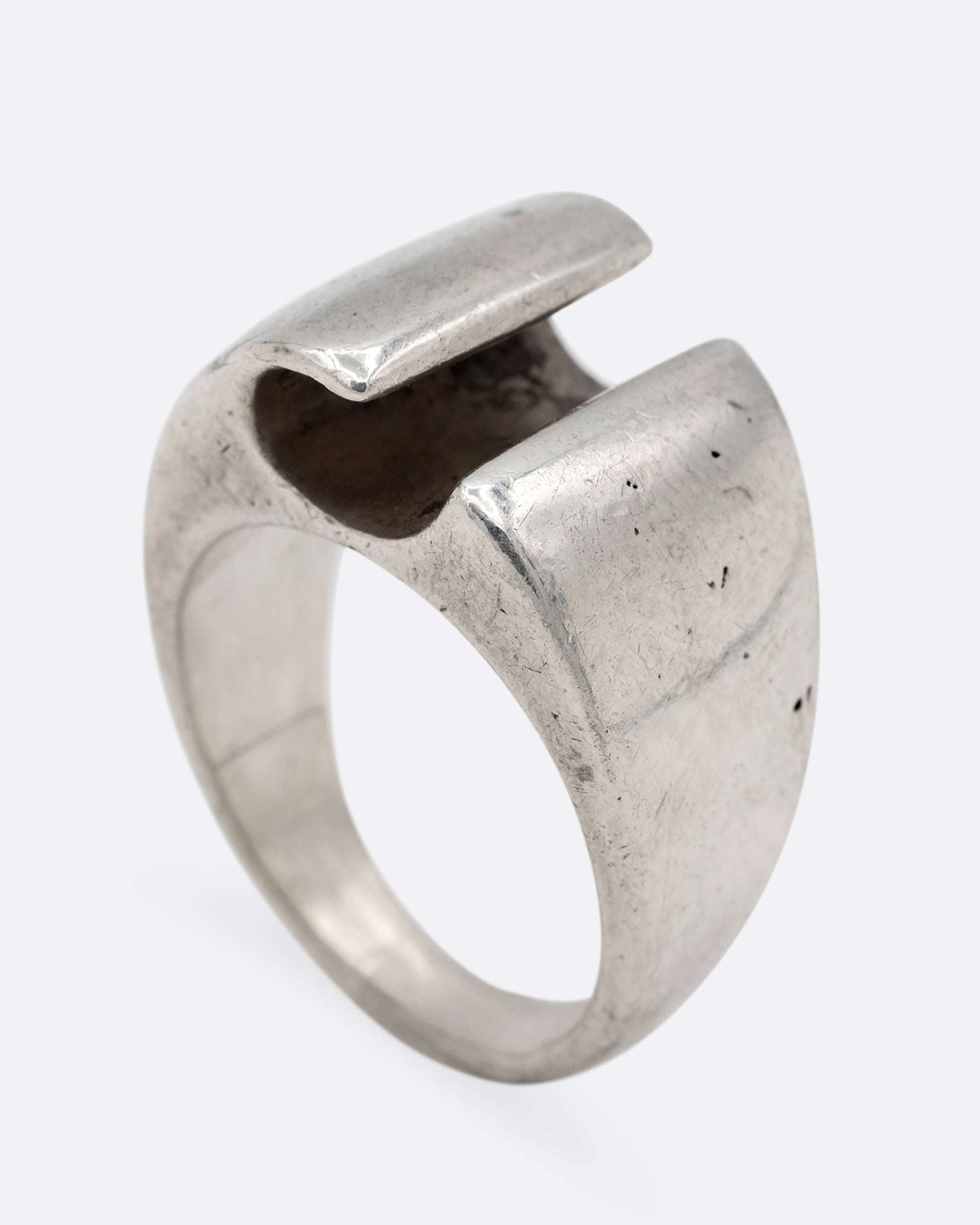 A silver ring with a notch in the front, shown from the side standing up.