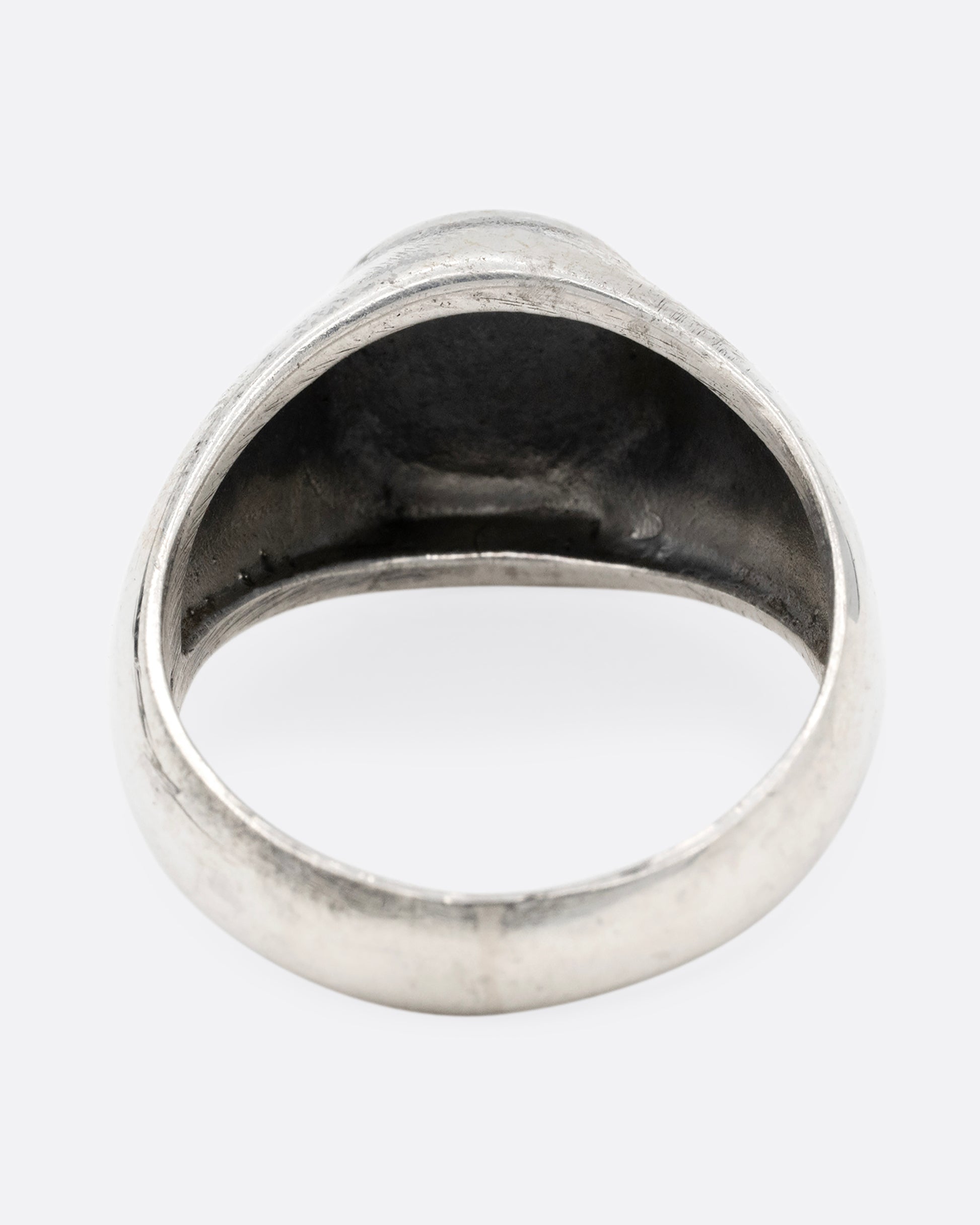 A silver signet ring with yin yang faces, shown from the back.
