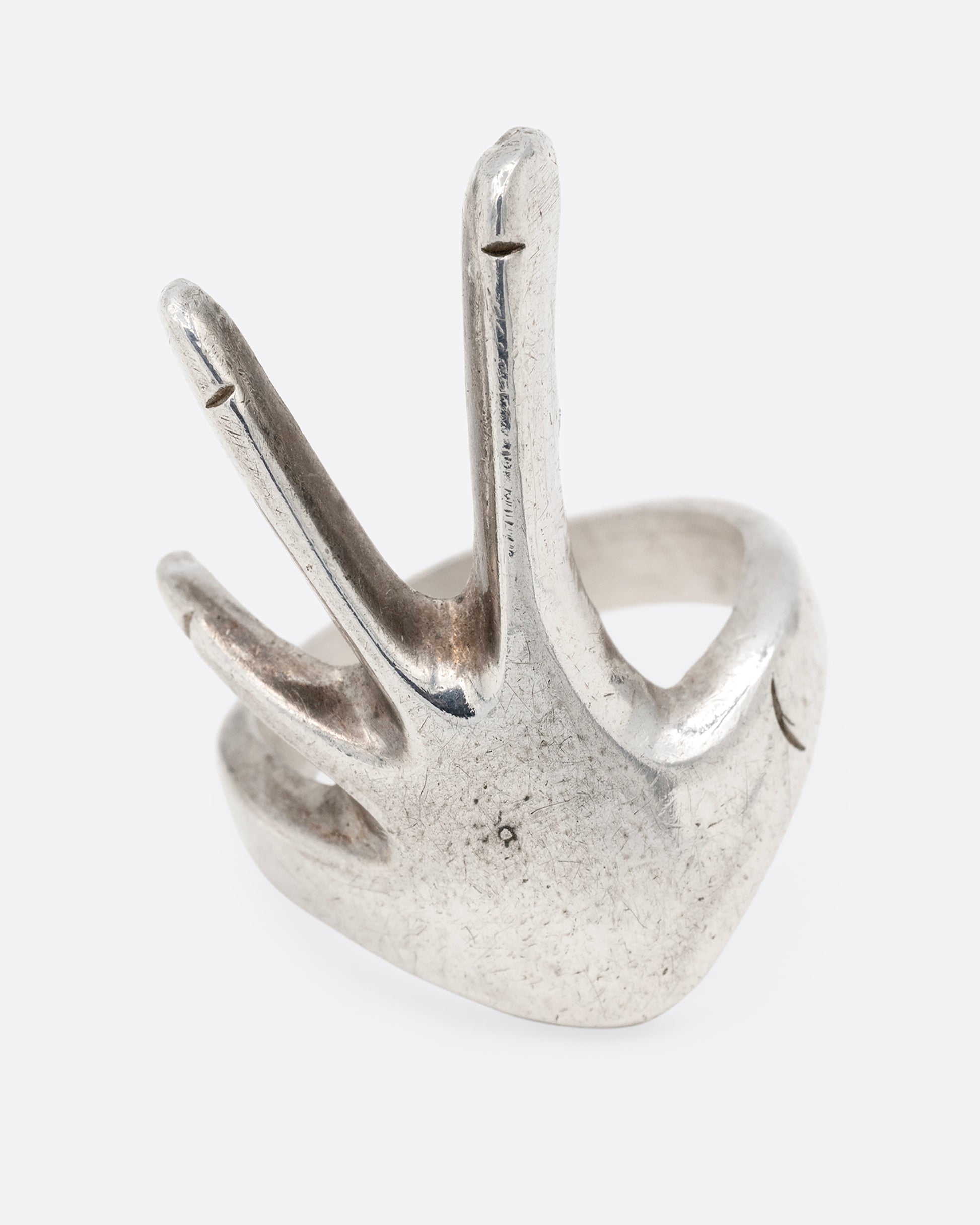 A silver hand shaped ring with long fingers, shown from the front.