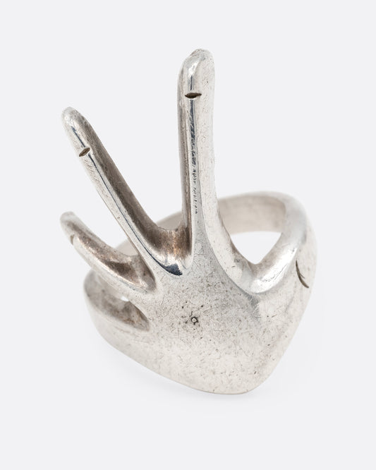 A silver hand shaped ring with long fingers, shown from the front.