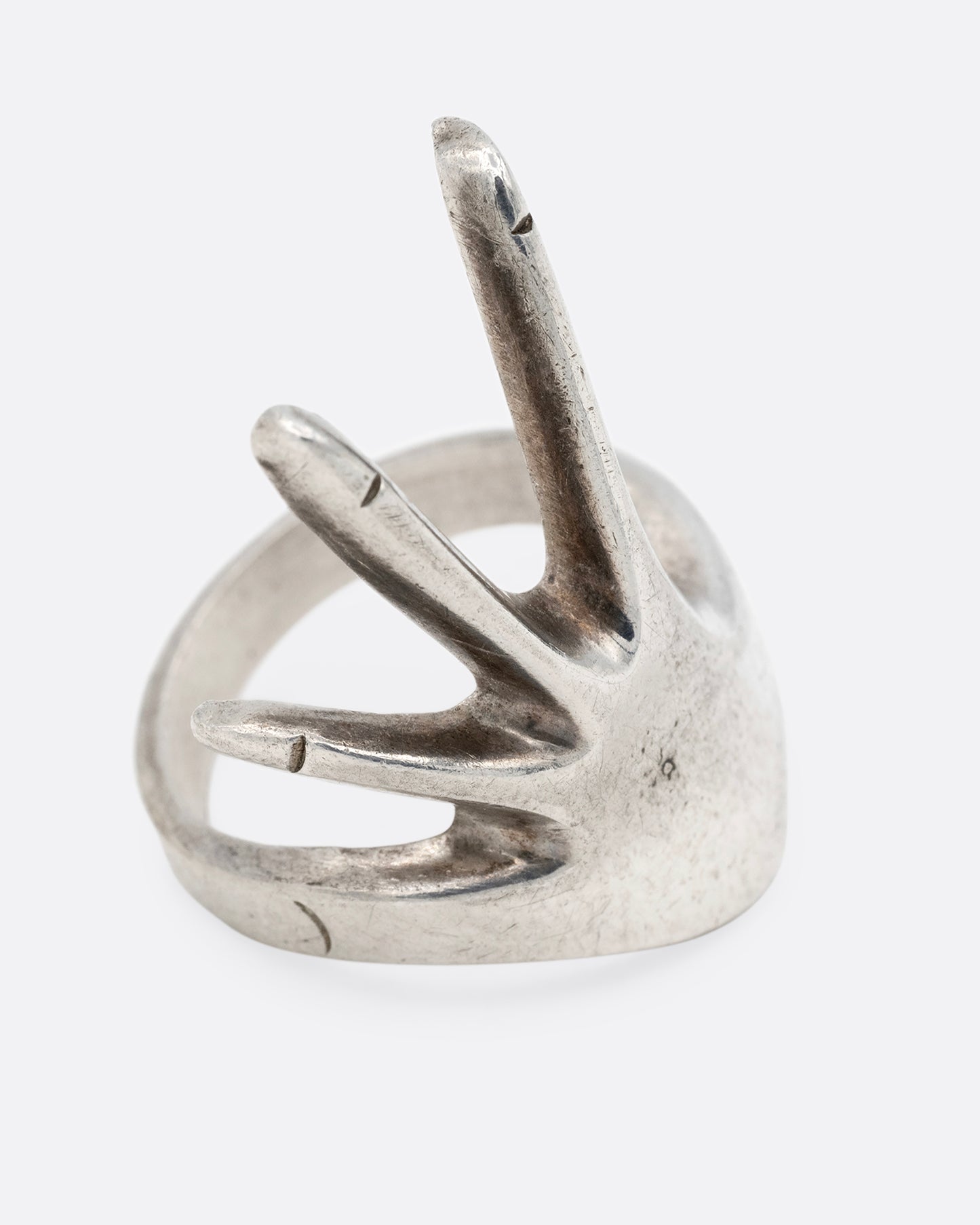 A silver hand shaped ring with long fingers, shown from the side.