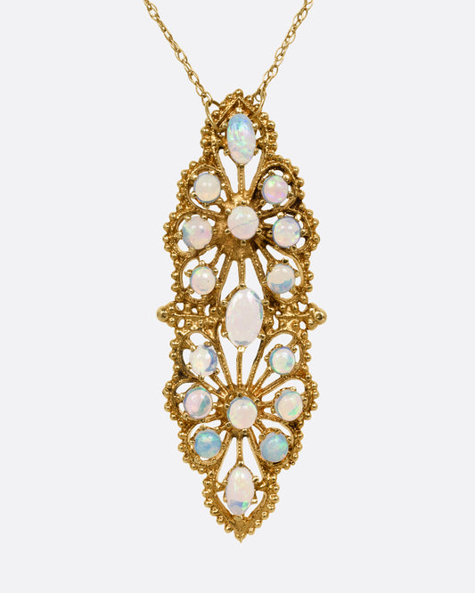 A yellow gold opal studded floral pendant, shown from the front on a cable chain.
