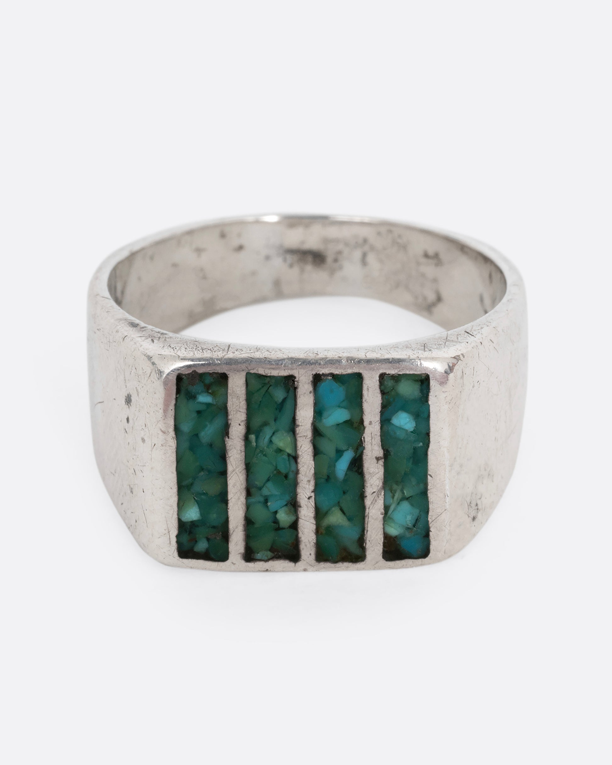 A silver ring with four rectangles inlaid with turquoise. Shown from the front.