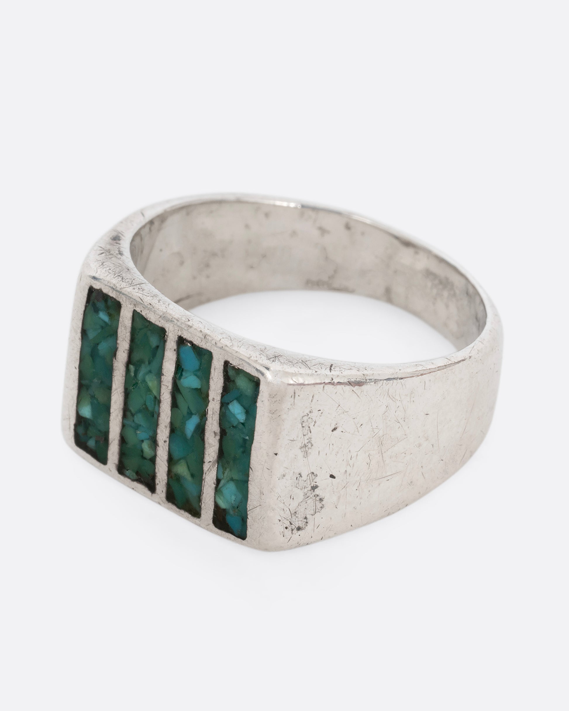 A silver ring with four rectangles inlaid with turquoise. Shown from the side.