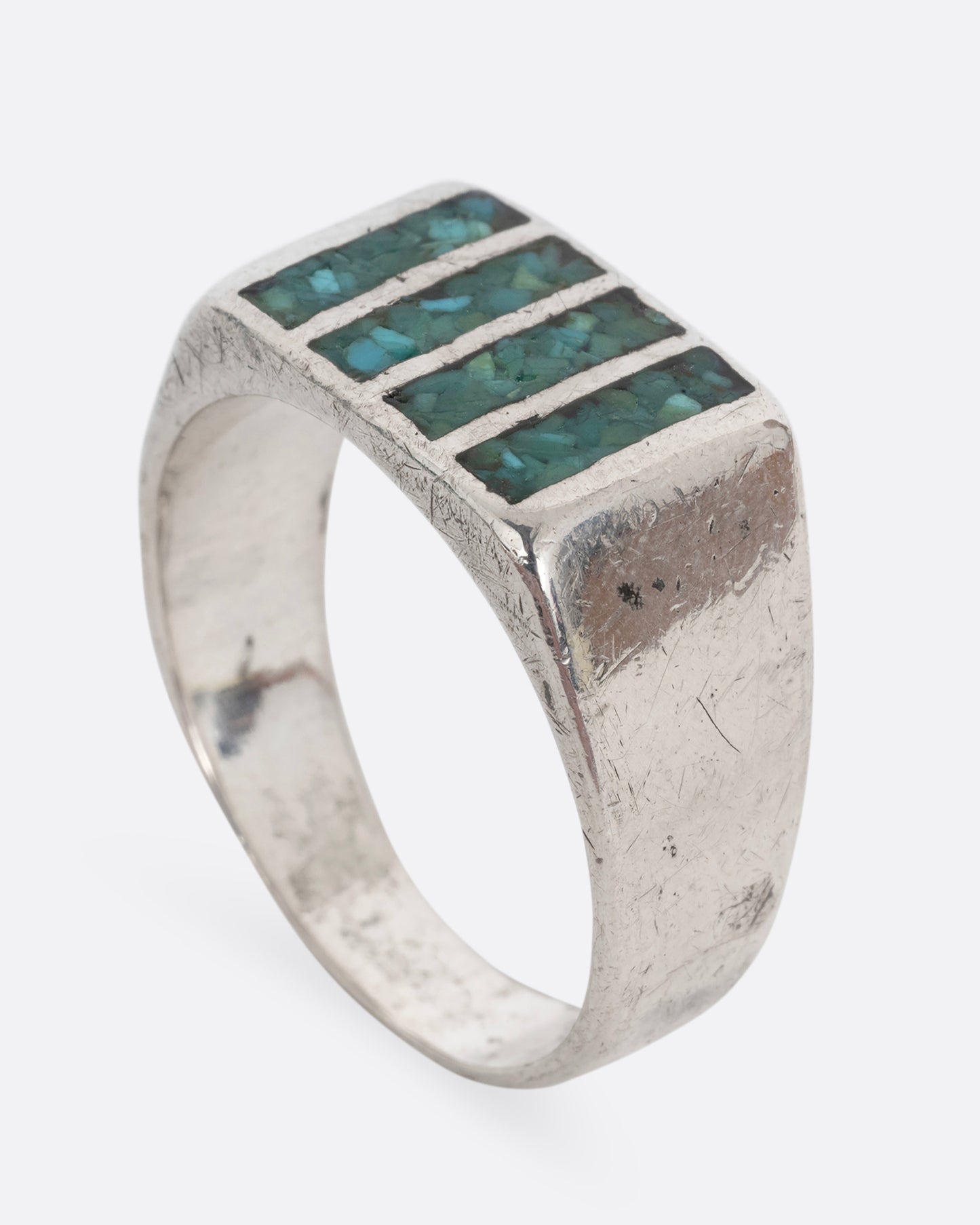 A silver ring with four rectangles inlaid with turquoise. Shown standing up from the side.