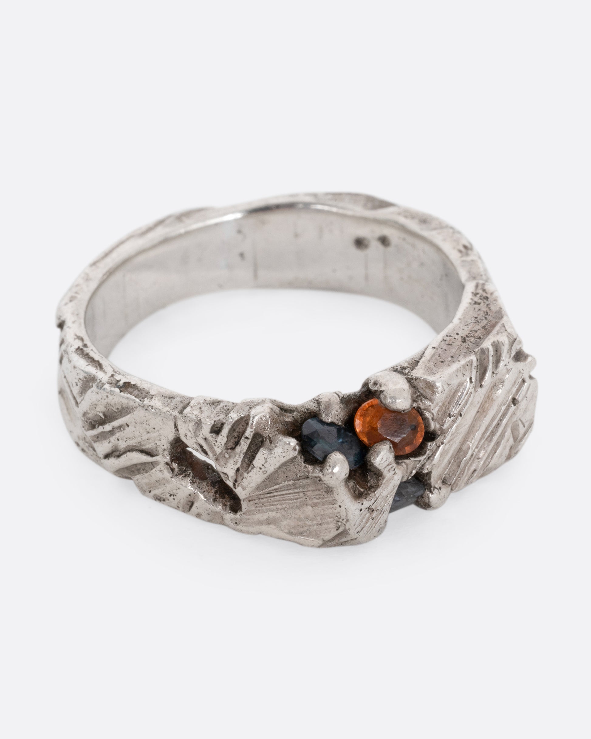 A silver ring with a citrine and amethyst embedded in it, shown from the side.