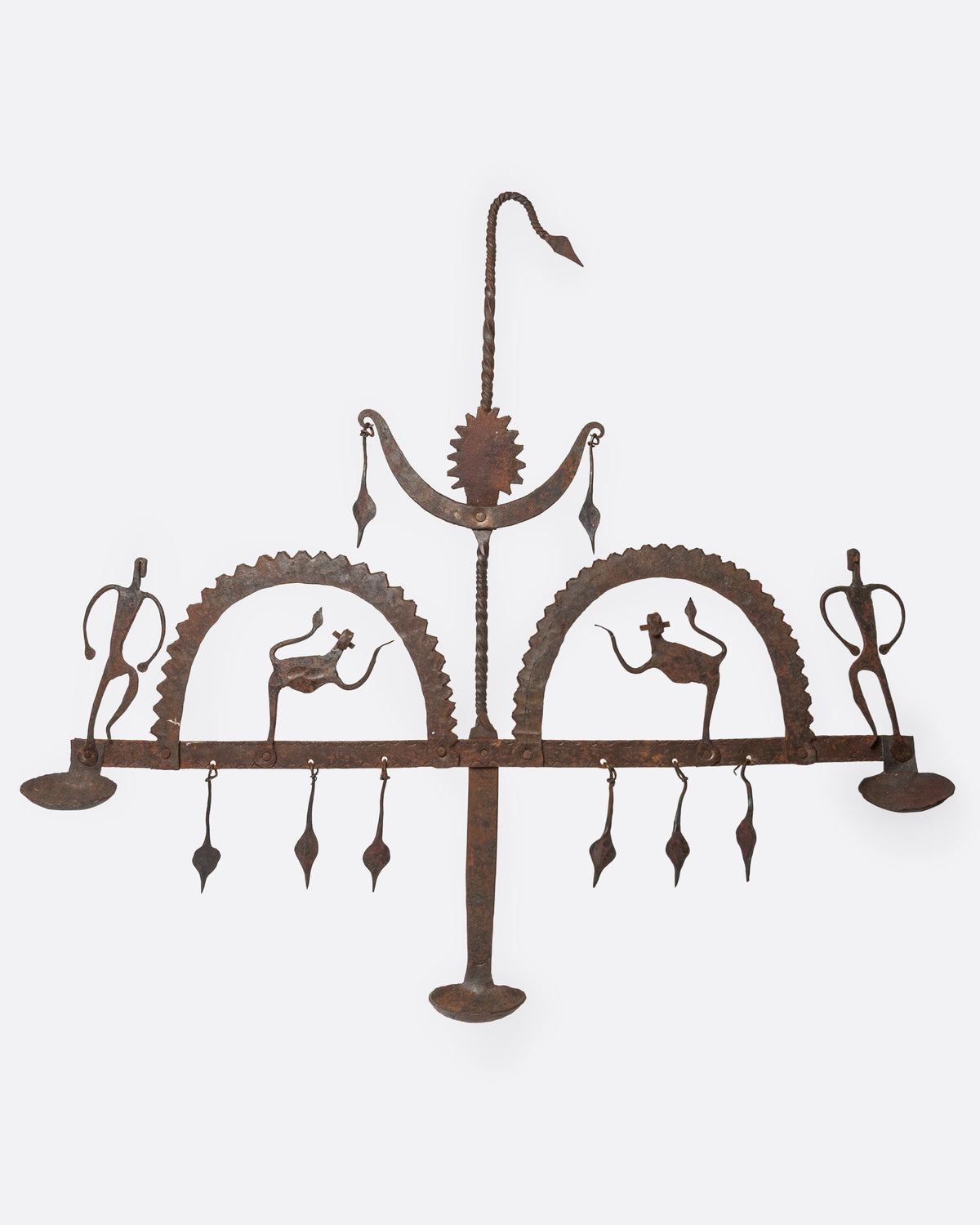 A cast iron hanging candle holder with small figures and fringe at its base and three spots for tea lights. Shown from the front.