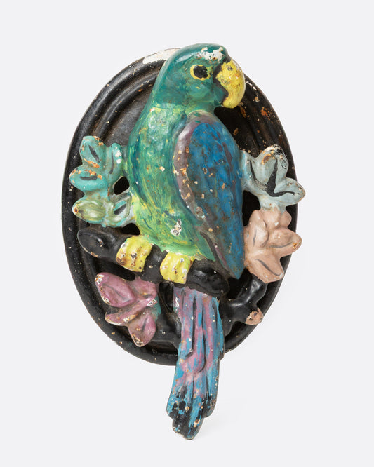 An iron parrot door knocker painted in bright colors, shown from the front.