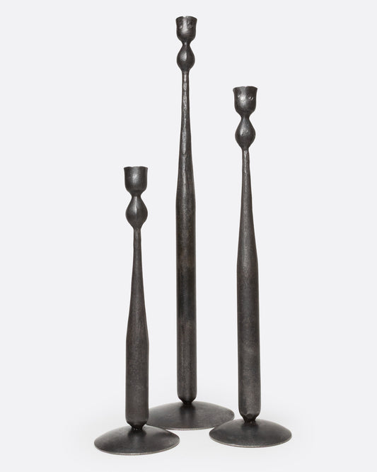 Three tall, slender iron candlestick holders in three different sizes, with flared circular bases, shown from the front.