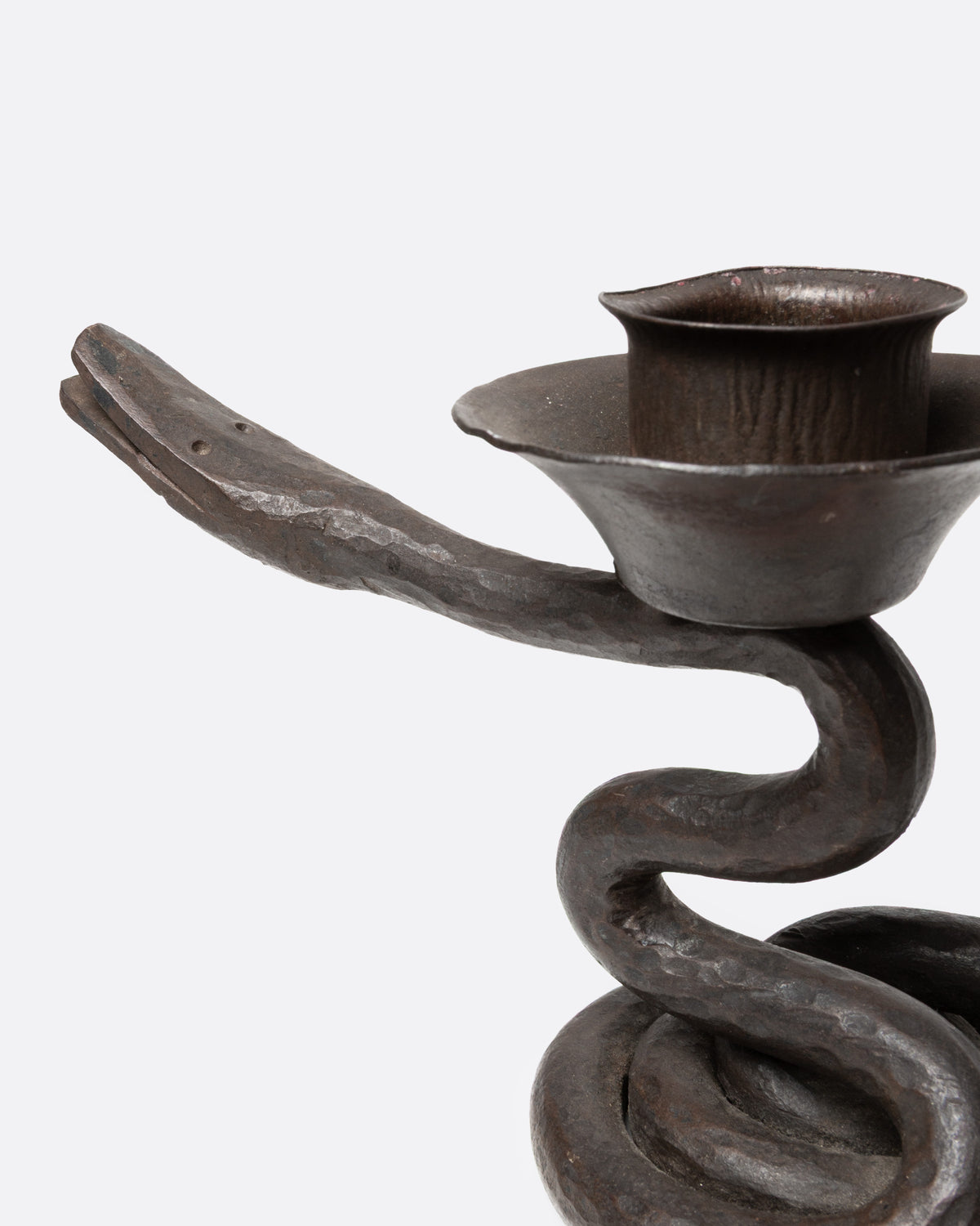A close up of an iron coiling iron snake candle holder.