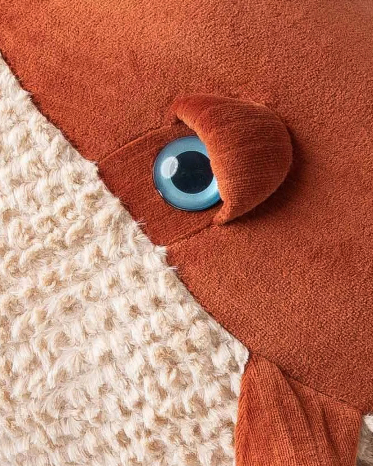 Close-up of the whale's blue eye against red velvet and cream knit