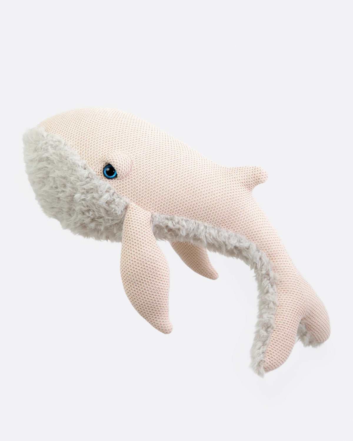 Large pale pink knit stuffed whale with a fluffy cream belly shown from the side.